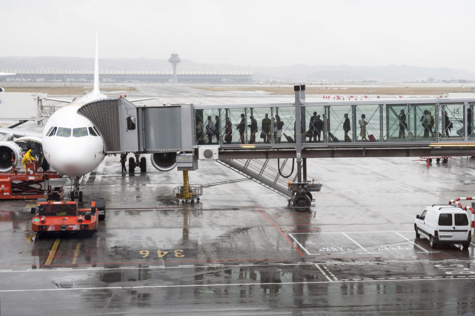 Passengers boarding an airplane through a boarding bridge in Madrid Barajas airport T4 terminal, Madrid, Spain