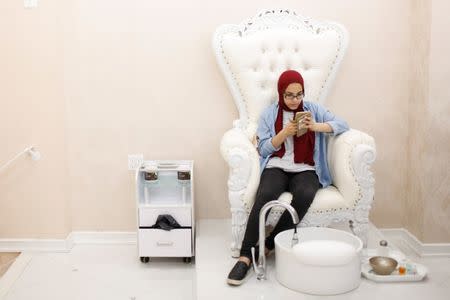 A Muslim woman uses her phone while waiting for a family member to receive treatment at the Le'Jemalik Salon and Boutique in Brooklyn, New York, U.S., June 21, 2017. Picture taken on June 21, 2017. REUTERS/Gabriela Bhaskar