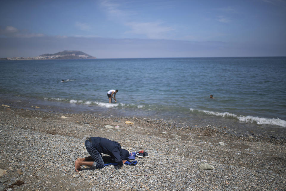 A boy prays before taking a swim in the Moroccan northern town of Fnideq, near the border of Morocco and Spain, at the Spanish enclave of Ceuta, on Tuesday, May 18, 2021. (AP Photo/Mosa'ab Elshamy)