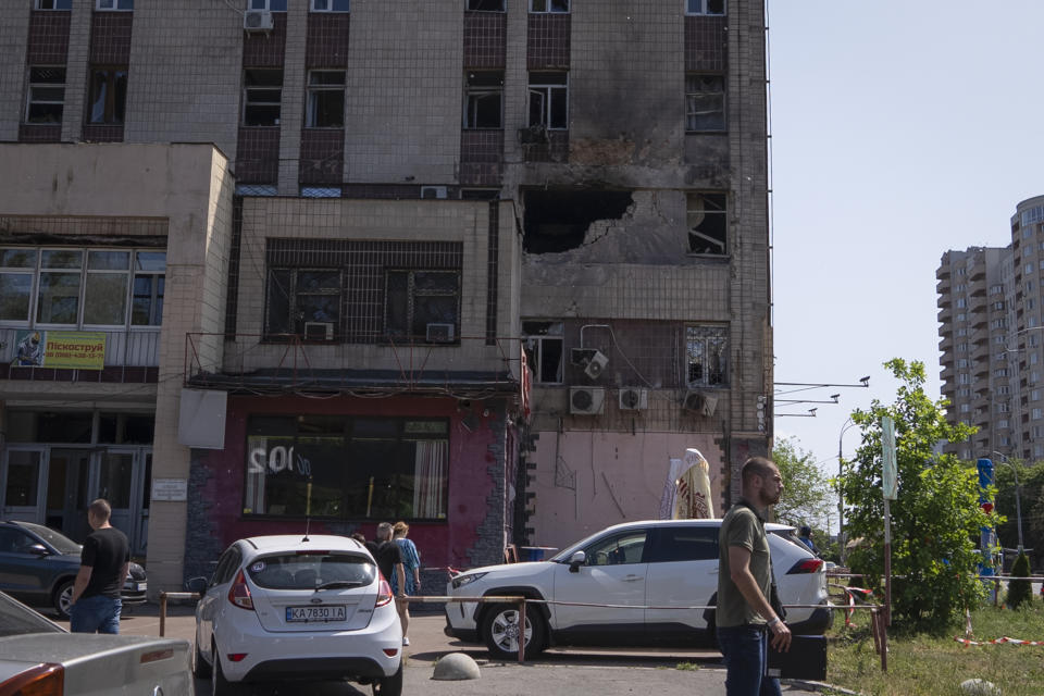 People pass by an apartment building damaged by a drone during a night attack in Kyiv, Ukraine, Sunday, May 28, 2023. Ukraine's capital was subjected to the largest drone attack since the start of Russia's war, local officials said, as Kyiv prepared to mark the anniversary of its founding on Sunday. (AP Photo/Vasilisa Stepanenko)