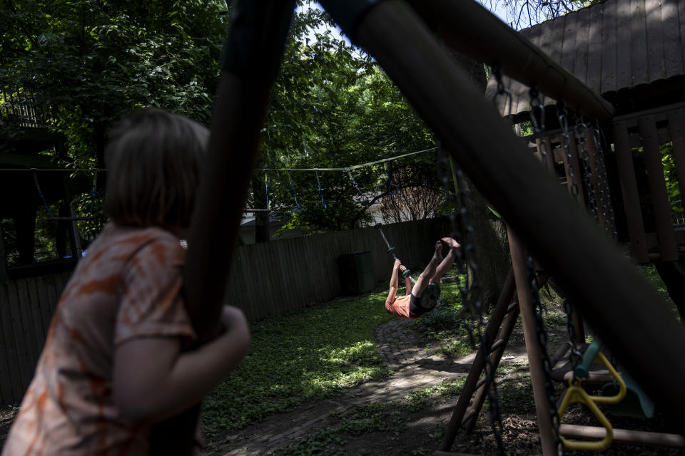 Sylvia Holm, 11, right, swings in her backyard while playing with her brother, George, at their home in Louisville, Ky., Saturday, June 3, 2023. (AP Photo/David Goldman)