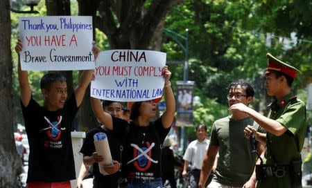 A policeman tries to stop anti-China protesters holding placards during a demonstration in front of the Philippines embassy in Hanoi, Vietnam July 17, 2016. REUTERS/Kham