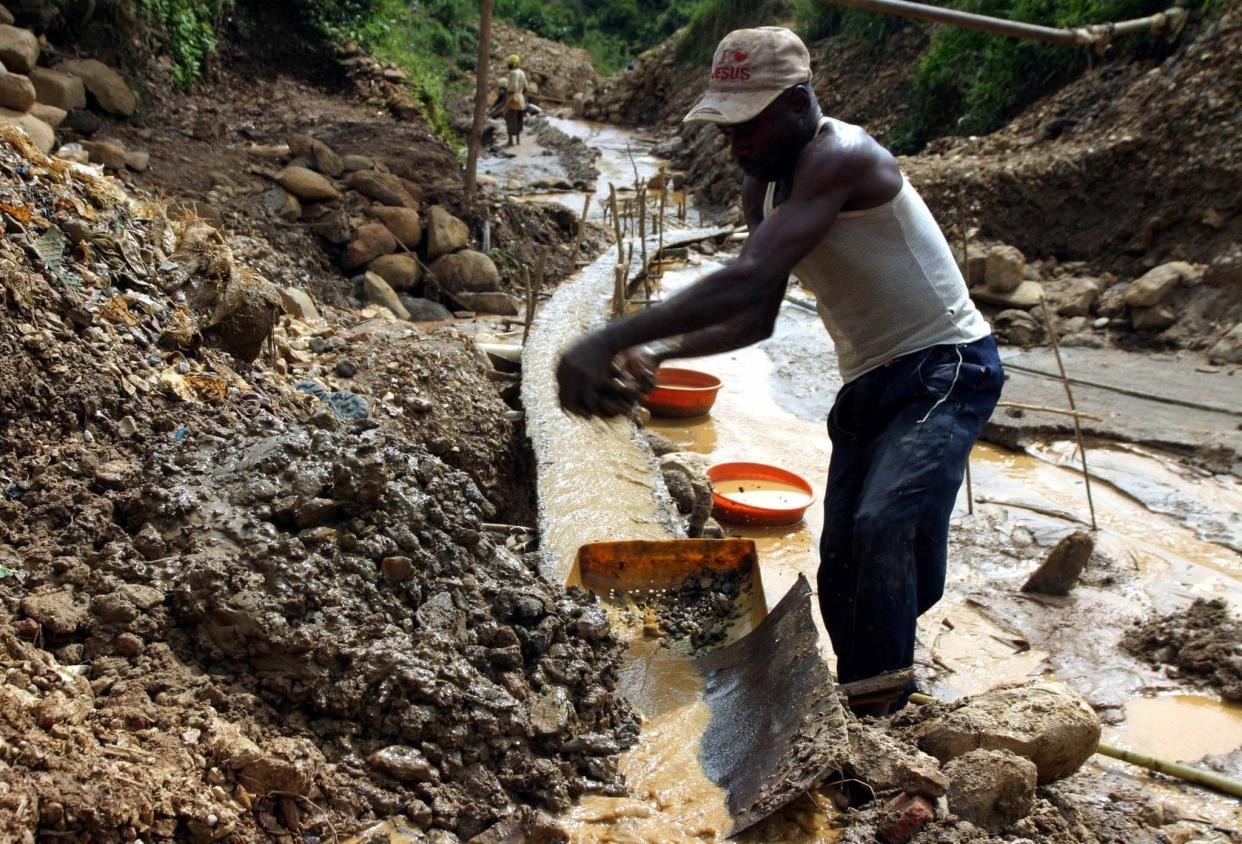 A Congolese man washes dirt and rocks in a river running through a gold mine near the eastern town of Kamituga