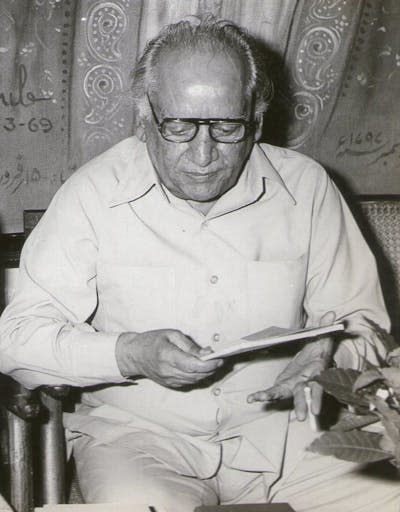 Black and white portrait of man wearing glasses sitting and reading.