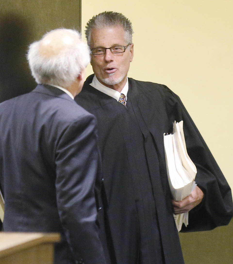 In this photo shot through a courtroom door, Judge Jerry Herberger, right, is pictured following a hearing in the Christopher Lane murder trial in Duncan, Okla, Wednesday, March 12, 2014. Herberger ruled that two teenagers charged with first-degree murder must face a trial in the shooting death of the Australian baseball player. (AP Photo/Sue Ogrocki)