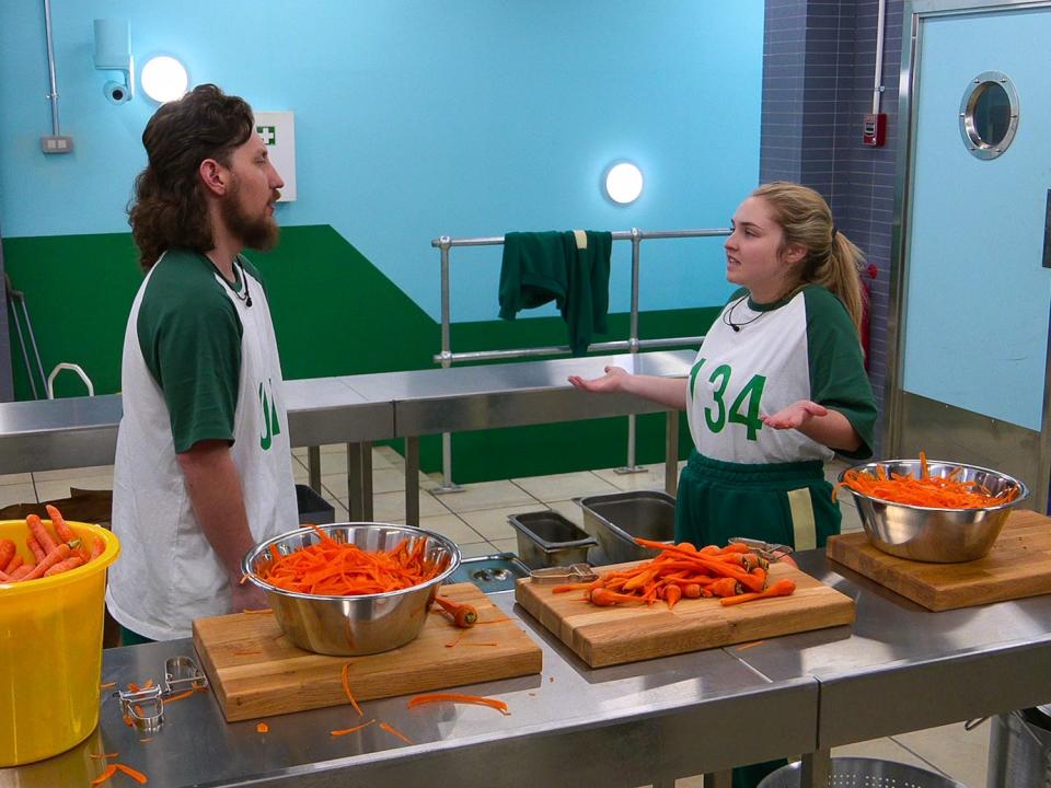 A man and a woman in front of a metal desk with carrots on them