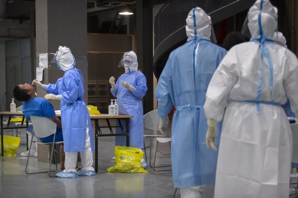 A worker in a protective suit swabs the throat of a man at a COVID-19 testing site for those who were potentially exposed to the coronavirus outbreak at a wholesale food market in Beijing, Wednesday, June 17, 2020. As the number of cases of COVID-19 in Beijing climbed in recent days following an outbreak linked to a wholesale food market, officials announced they had identified hundreds of thousands of people who needed to be tested for the coronavirus. (AP Photo/Mark Schiefelbein)