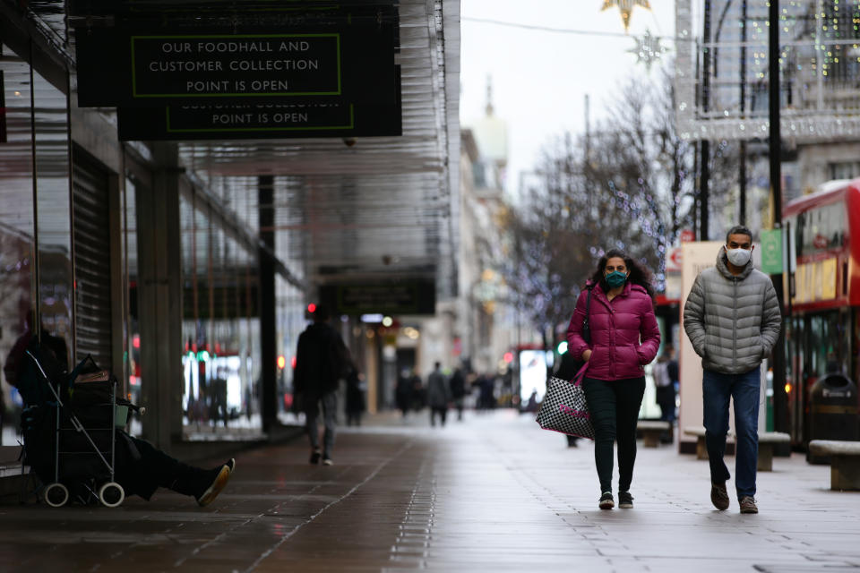 People wearing face masks walk past temporarily-closed stores on Oxford Street in London, England, on December 21, 2020. London spent its second day of what could be months under newly-introduced 'Tier 4' coronavirus restrictions today. Under Tier 4 rules non-essential shops and many other businesses including gyms and hairdressers must close, with people instructed to stay at home other than for exempted circumstances including travel to work or education. Indoor mixing between those in different households is also banned under the new tier, upending Christmas plans for a huge swathe of the population. Concern over a more infectious strain of the coronavirus in the UK has meanwhile seen dozens of countries ban arrivals from Britain, with food supplies also disrupted after France closed the cross-Channel freight route from Dover. (Photo by David Cliff/NurPhoto via Getty Images)