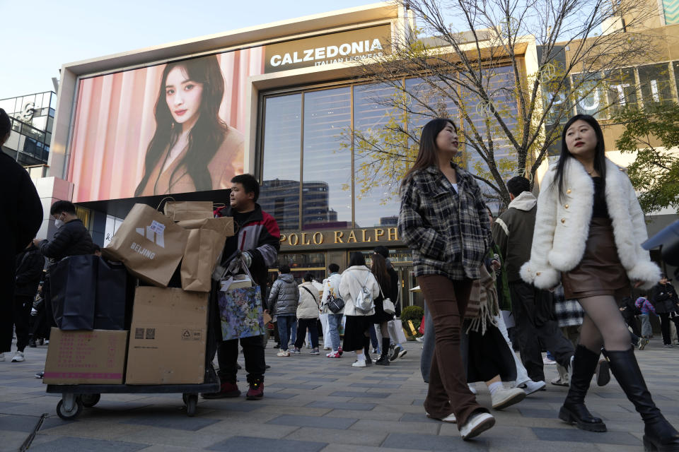 A delivery man collects packages as shoppers visit a popular mall district in Beijing, Saturday, Nov. 18, 2023. Chinese leaders have wrapped up a two-day annual meeting to set economic priorities for the coming year, the official Xinhua News Agency reported Tuesday Dec. 12, 2023 without giving details of what was decided. (AP Photo/Ng Han Guan)