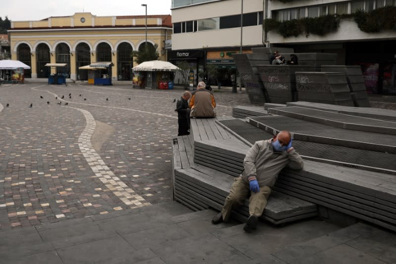 A man wearing a protective face mask rests on Monastiraki square, following an outbreak of the coronavirus disease (COVID-19), in Athens