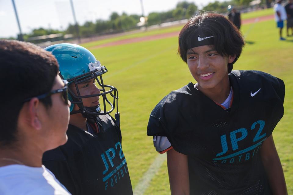 St. John Paul II wide receiver Jacob Carrillo (1), right, jokes around with corner Dylan Olmos, left, and offensive lineman Luis Armando Rodriguez Cruz, center, as they take a break during a team practice on Thursday, September 15, 2022, in Avondale. Carrillo was diagnosed with cancer and continues to receive chemotherapy as he plays on the football team.