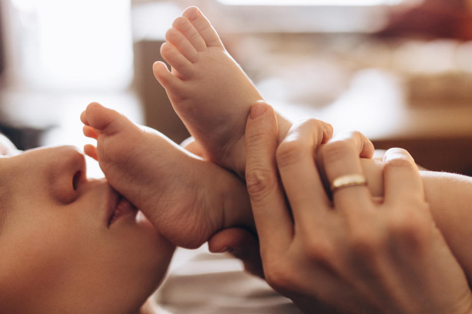 Adult gently holding a baby's foot close to their face, expressing affection