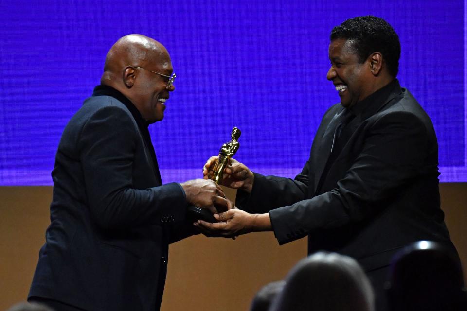 Samuel L Jackson receives his honorary Oscar from Denzel Washington (AFP via Getty Images)