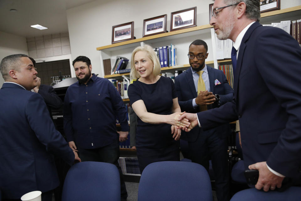 Democratic presidential candidate Sen. Kirsten Gillibrand, D-N.Y., center, shakes hands with law professor Michael Kagan, right, while speaking with law students at a legal clinic at the University of Nevada, Las Vegas, Thursday, March 21, 2019, in Las Vegas. The legal clinic works with unaccompanied immigrant children.(AP Photo/John Locher)