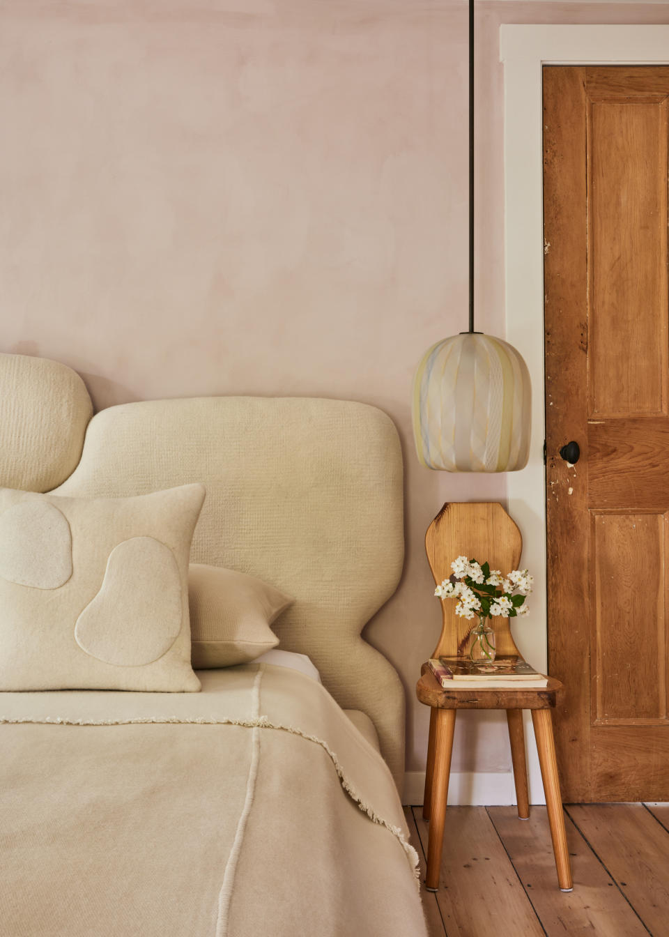 A bedroom with fresh flowers next to the headboard