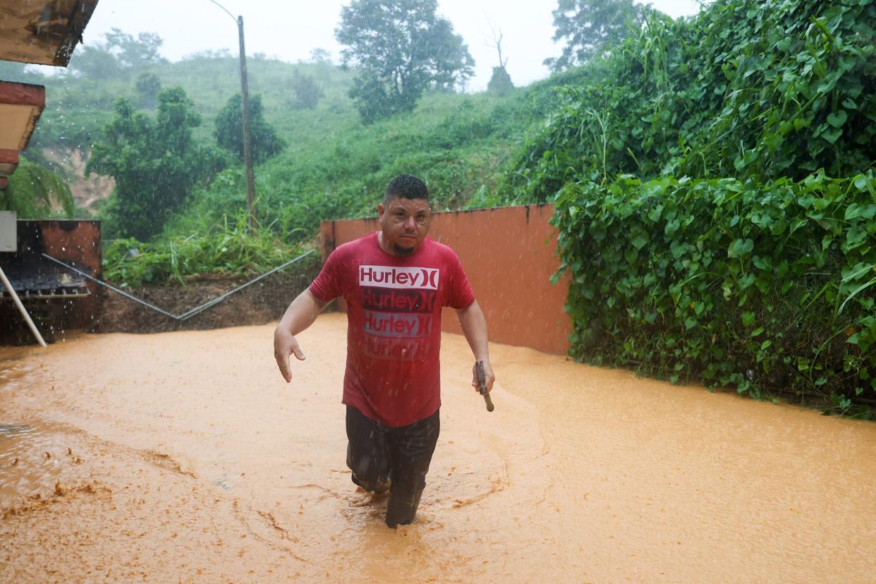 A man walks on a road flooded by Hurricane Fiona in Cayey, Puerto Rico, Sunday, Sept. 18, 2022.