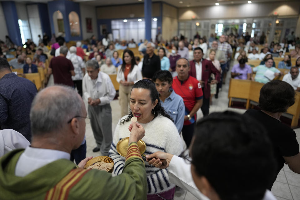The Rev. Edwing Roman gives communion to parishioners during Mass at St. Agatha Catholic Church, which has become the spiritual home of the growing Nicaraguan diaspora, Sunday, Nov. 5, 2023, in Miami. For Father Roman, as well as the auxiliary bishop of Managua, and many worshippers who have had to flee or were exiled from Nicaragua recently, the Sunday afternoon Mass at the Miami parish is not only a way to find solace in community, but also to keep pushing back against the Ortega regime's violent suppression of all critics, including many Catholic leaders. (AP Photo/Rebecca Blackwell)