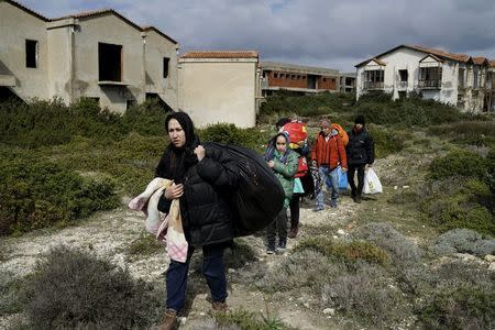 Afghan refugees walk through a beach where they will wait to board a dinghy sailing off for the Greek island of Chios, while they try to travel from the western Turkish coastal town of Cesme, in Izmir province, Turkey, March 6, 2016. REUTERS/Umit Bektas