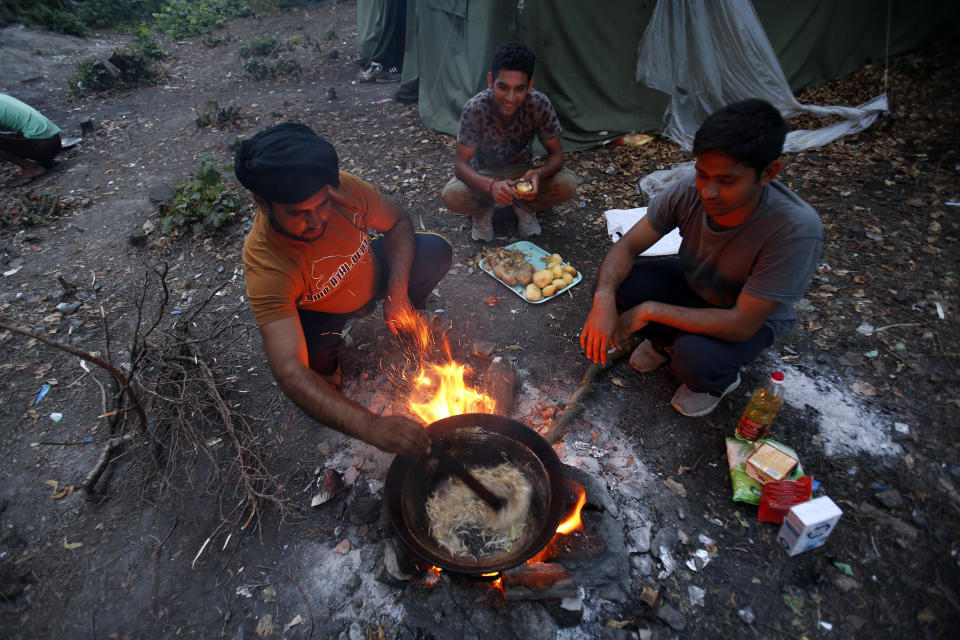 In this photo taken on Tuesday, Aug. 14, 2018, migrants prepare dinner in a makeshift migrant camp in Bihac, 450 kms northwest of Sarajevo, Bosnia. Impoverished Bosnia must race against time to secure proper shelters for at least 4,000 migrants and refugees expected to be stranded in its territory during coming winter. The migrant trail shifted toward Bosnia as other migration routes to Western Europe from the Balkans were closed off over the past year. (AP Photo/Amel Emric)