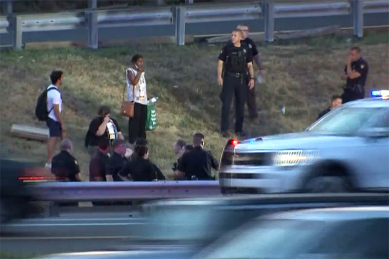 Civilians and police stand together along an area of the New Jersey Turnpike after a bus crash Tuesday. (NBC New York)