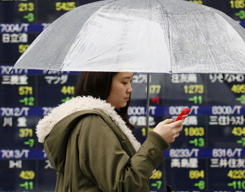 A woman walks by an electronic stock board of a securities firm in Tokyo, Thursday, March 20, 2014. Asian stocks inched down Thursday after comments from the new head of the Federal Reserve suggested U.S. interest rates could rise sooner than financial markets were anticipating. (AP Photo/Koji Sasahara)