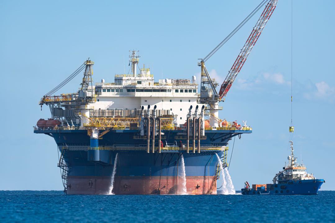 Offshore Accommodation platform working on oil and gas field development project with a supply vessel sailing nearby