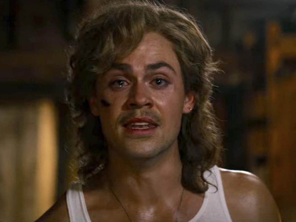 A young man (Dacre Montgomery) with a mullet haircut looks tormented into the camera.