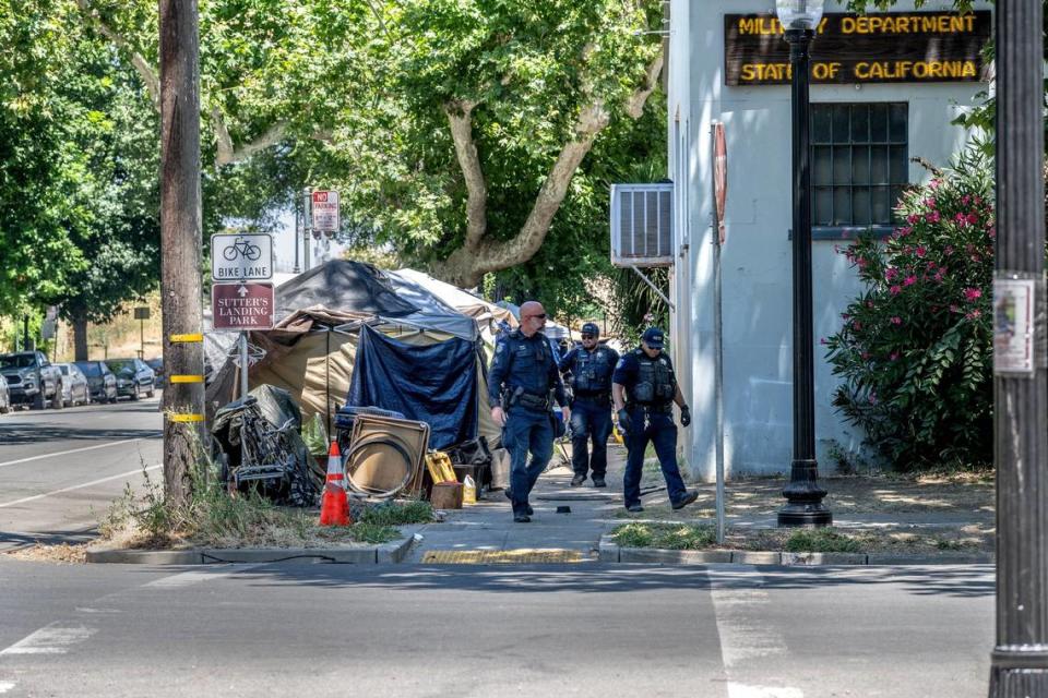 Law enforcement patrol a tent encampment at the intersection of C and 28th on Tuesday, July 18, 2023. The city has given notices to dozens of people living in tents on the sidewalks in that area, near Leland Stanford Park, telling them to move by Wednesday. The notices cite violation of city codes regarding sidewalk obstruction and storage of personal property on public property.