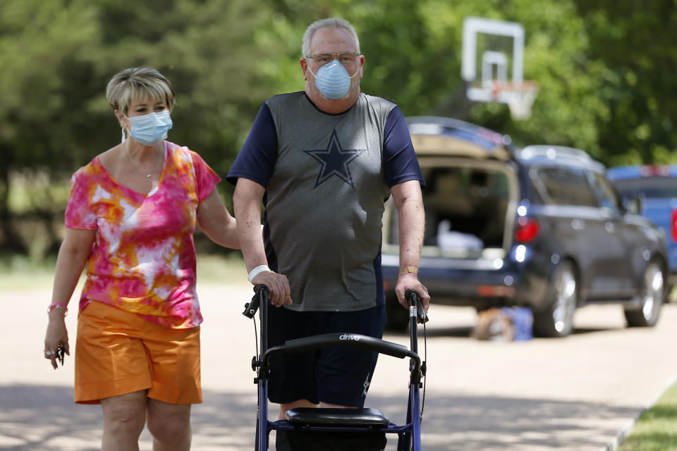 Terri Donelson, left, and her husband, Stephen, walk up their driveway to see friends and family awaiting him at his home in Midlothian, Texas on Friday, June 19, 2020, after his 90-day stay in the Zale Hospital on the UT Southwestern Campus. Donelson’s family hadn’t left the house in two weeks after COVID-19 started spreading in Texas, hoping to shield the organ transplant recipient. Yet one night, his wife found him barely breathing, his skin turning blue, and called 911. (AP Photo/Tony Gutierrez)