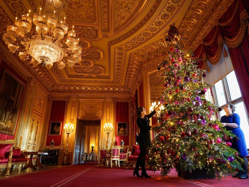 Members of the Royal Collection Trust staff put the finishing touches to a Christmas tree in the Crimson Drawing Room, during a photo call for Christmas decorations at Windsor Castle, Berkshire on November 24, 2022.