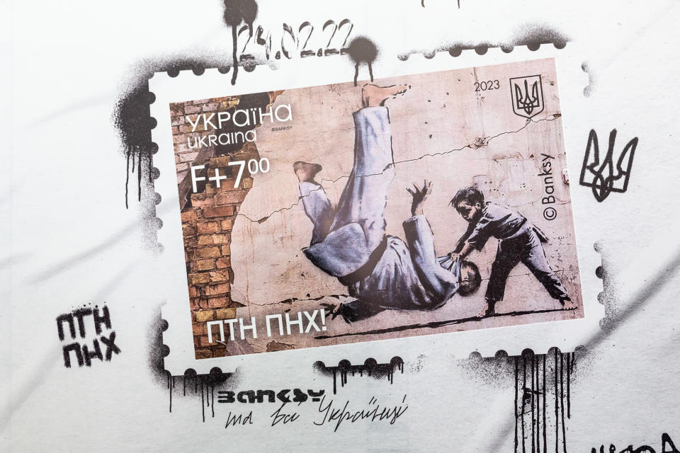 A billboard presents the new FCK PTN stamps which has its premiere on the anniversary of Russian invasion and uses the artwork by Banksy in the Central Post Office in Old Town Kyiv, the capital of Ukraine on February 24, 2023. As the full scale invasion of Ukraine by the Russian forces marks one year Ukrainian national post presents another of its collection of stamps with artworks directly connected with the war. The one year anniversary stamp uses Banksy graffiti from Borodyanka which resembles Vladimir Putin being flipped during a judo match with a young boy. The stamp is named FCK PTN. (Photo by Dominika Zarzycka/NurPhoto via Getty Images)