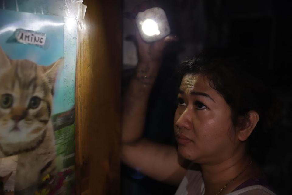 印尼籍租戶 Sa Sa 拿著手電筒，在房間哭尋愛貓。