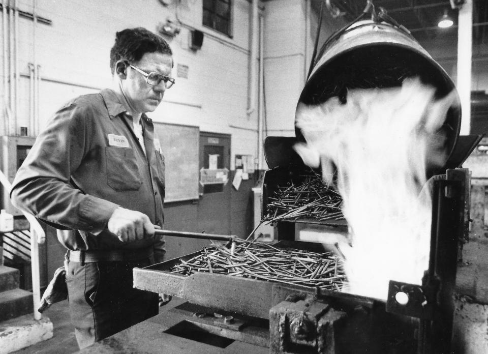 Akron Steel Treating Co. employee Kevin Robenstine looks over screws running through a shaker furnace in 1988 at the South Broadway plant.