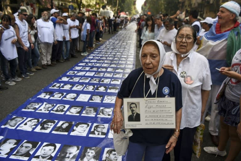 Members of the Madres de Plaza de Mayo and Abuelas de Plaza de Mayo human rights organizations and thousands of demonstrators stand by a large banner with portraits of people who disappeared during the 1976-1983 military dictatorship, in Buenos Aires