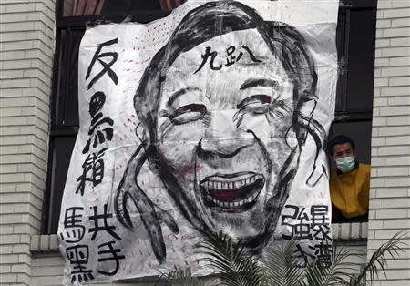 A protester looks out from a window next to a cartoon depicting Taiwan's President Ma Ying-jeou at Taiwan's legislature in Taipei, March 21, 2014. REUTERS/Patrick Lin