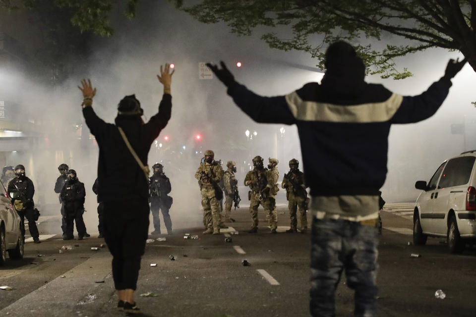 Demonstrators stand in front of federal officers during a Black Lives Matter protest at the Mark O. Hatfield United States Courthouse Friday, July 24, 2020, in Portland, Ore. (AP Photo/Marcio Jose Sanchez)