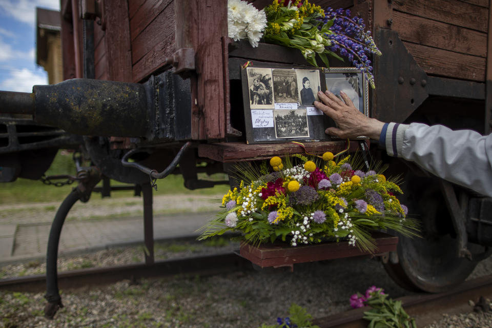 A man lays pictures of relatives who were deported on the steps of old wagons at the Naujoji Vilnia railway station in Vilnius, Lithuania, Monday, June 14, 2021, as Lithuania marked the mass deportation 80 years ago by the Soviet Union that was occupying the Baltic nation. Deportation started on June 14, 1941, where some 280,000 people were deported to Siberian gulags, a year after Soviet troops had occupied Lithuania. (AP Photo/Mindaugas Kulbis)