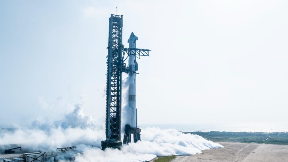 Eine silberne Rakete steht neben einem riesigen metallenen Startturm.