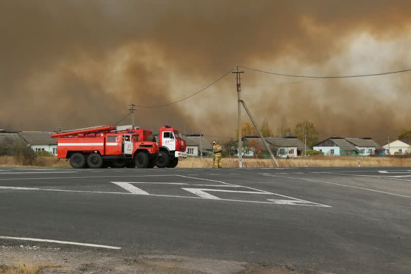 Fire trucks are seen on the road as smoke rises from the site of a fire at an ammunition depot in Ryazan Region
