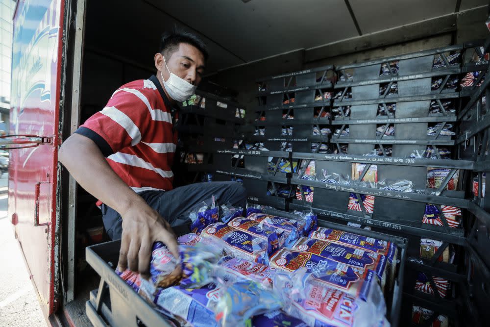 A man unloads fresh loaves of bread at a convenience store in Petaling Jaya March 25, 2020. — Picture by Ahmad Zamzahuri