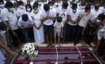 Family members of Sri Lankan factory manager Priyantha Kumara who was lynched by a Muslim mob in Pakistan for alleged blasphemy gather around the grave during his burial in Colombo, Sri Lanka, Wednesday, Dec. 8, 2021. (AP Photo/Eranga Jayawardena)