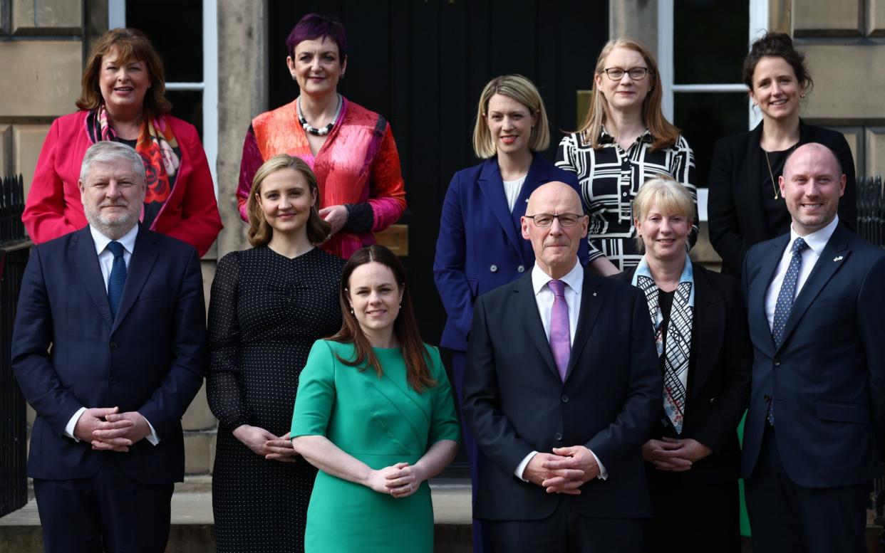 Newly appointed First Minister of Scotland John Swinney (bottom, C-R) and deputy First Minister Kate Forbes (bottom, C-L) pose for a photo with their new cabinet including (top row, L-R) Cabinet Secretary for Transport Fiona Hislop, Cabinet Secretary for Justice and Home Affairs Angela Constance, Cabinet Secretary for Education and Skills Jennifer Gilruth, Cabinet Secretary for Social Justice Shirley-Anne Somerville, Cabinet Secretary for Rural Affairs, Land Reform and Islands Mairi Gougeon and (second row, L-R) Cabinet Secretary for Constitution, External Affairs and Culture Angus Robertson, Cabinet Secretary with responsibility for Net Zero and Energy portfolio MÃ iri McAllan, Cabinet Secretary with responsibility for Finance and Local Government Shona Robison and Cabinet Secretary for Health and Social Care Neil Gray outside Bute House on May 8, 2024 in Edinburgh, Scotland
