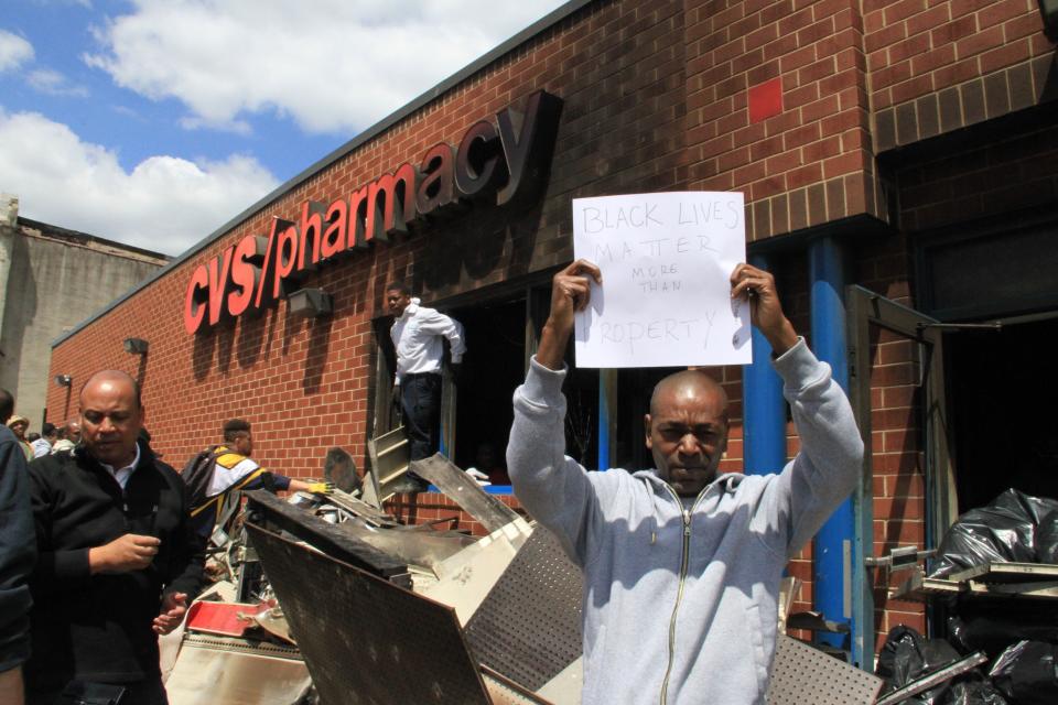 BALTIMORE, MD - APRIL 28: People protest near the CVS pharmacy that was set on fire yesterday during rioting after the funeral of Freddie Gray, on April 28, 2015 in Baltimore, Maryland. Protests following the death of Freddie Gray from injuries suffered while in police custody have turned violent with people throwing debris at police and media and burning cars and businesses. (Photo by Muhammed Bilal Kenasari/Anadolu Agency/Getty Images)