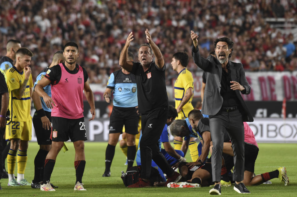 Eduardo Domínguez, coach of Estudiantes de La Plata, right, asks for help for Javier Altamirano during an Argentine soccer league match against Boca Juniors in La Plata, Argentina, Sunday, March 17, 2024. The match was suspended after Altamirano was taken off the field in an ambulance. (AP Photo/Ignacio Amiconi)