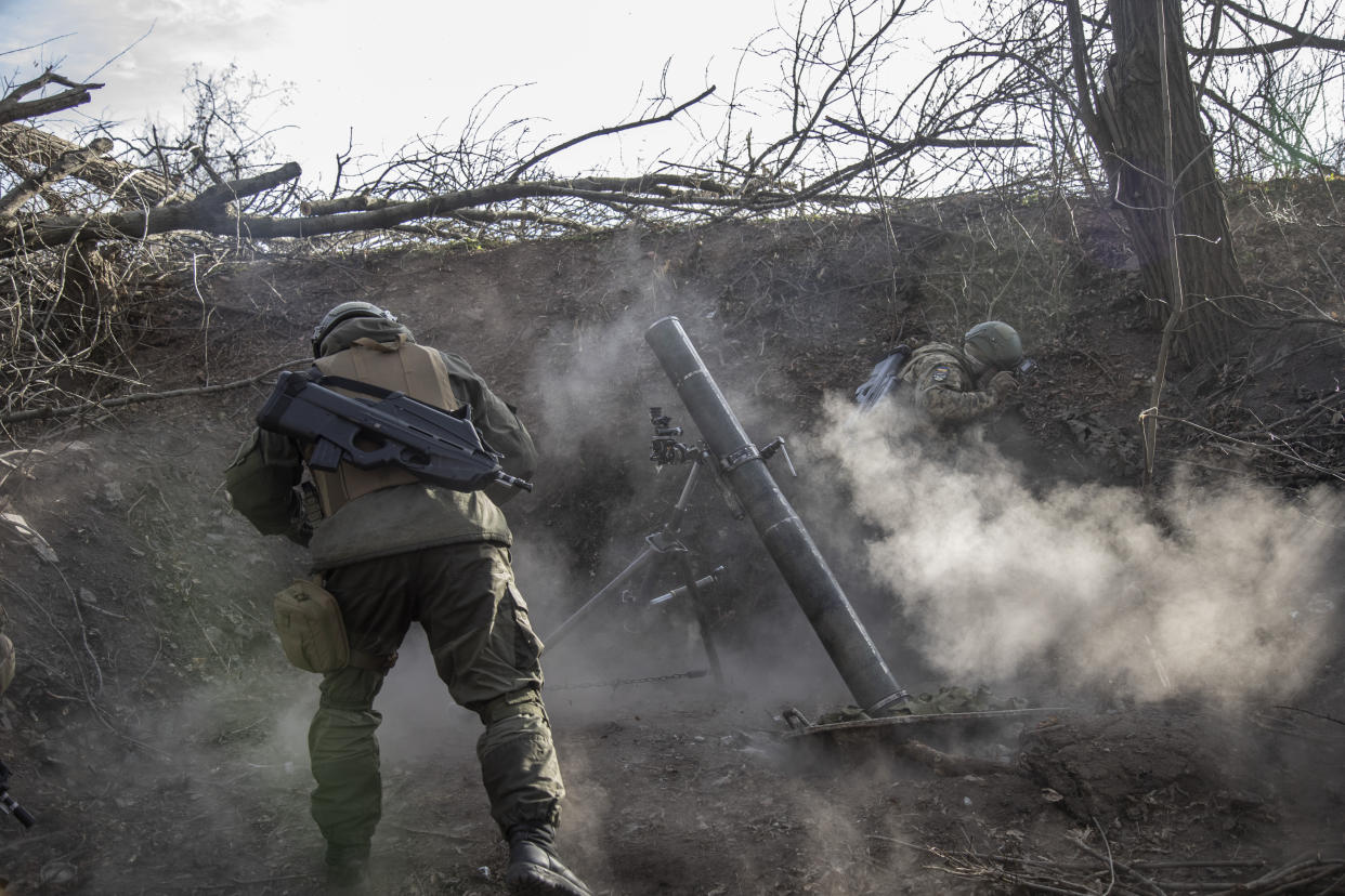 Ukrainian servicemen take cover as they fire a mortar load.