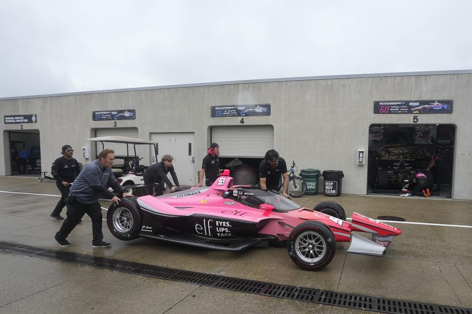 The crew for Katherine Legge, of England, pushes the car to the garage during a practice session for the Indianapolis 500 auto race at Indianapolis Motor Speedway, Tuesday, May 14, 2024, in Indianapolis. Practice was cancelled due to rain. (AP Photo/Darron Cummings)