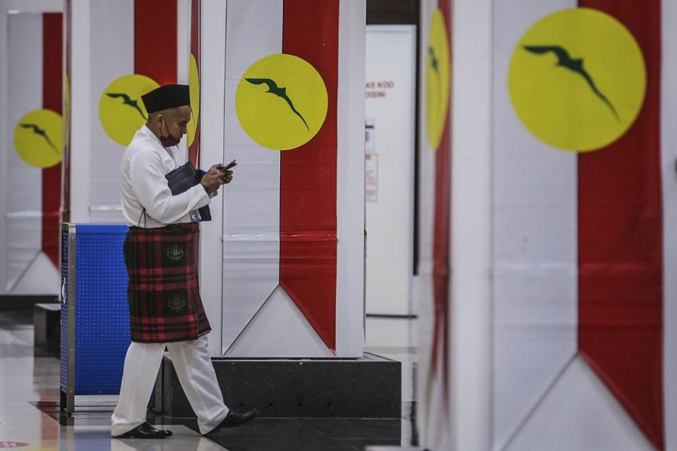 An Umno member arrives for the 2021 Umno annual general assembly in Kuala Lumpur March 27, 2021. ― Picture by Hari Anggara