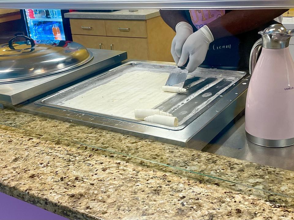 Ice cream being rolled on a frozen plate at Curly Cream Rolled Icecream.