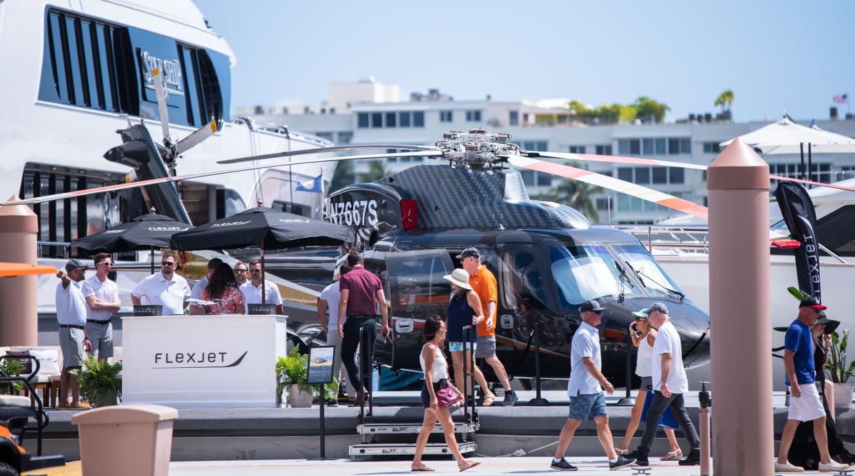 Guests walk past a Sikorsky S-76C helicopter parked at the Palm Beach International Boat Show on Saturday, March 25, 2023, in downtown West Palm Beach. Thousands flock annually to downtown West Palm Beach to see boats, catamarans, superyachts and other watercraft on display in the Lake Worth Lagoon during the Palm Beach International Boat Show.