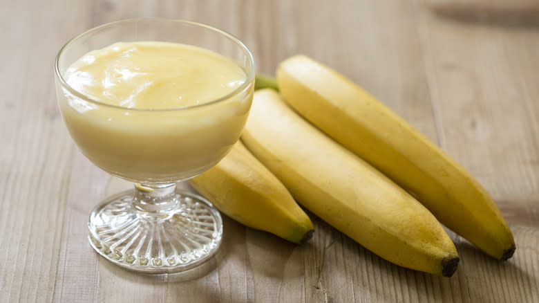 banana pudding in a glass dish next to three bananas